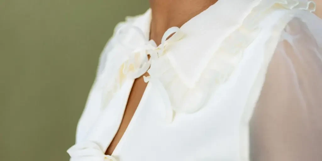 Close view of a person wearing an elegant white blouse with a delicate ribbon detail