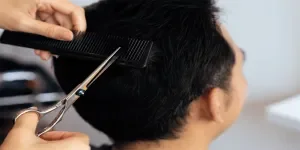 Closeup asian female barber making haircut for male customer