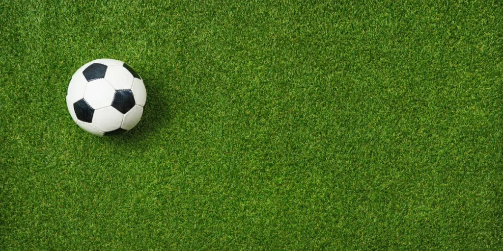 Closeup of soccer ball on textured green grass - center, midfield