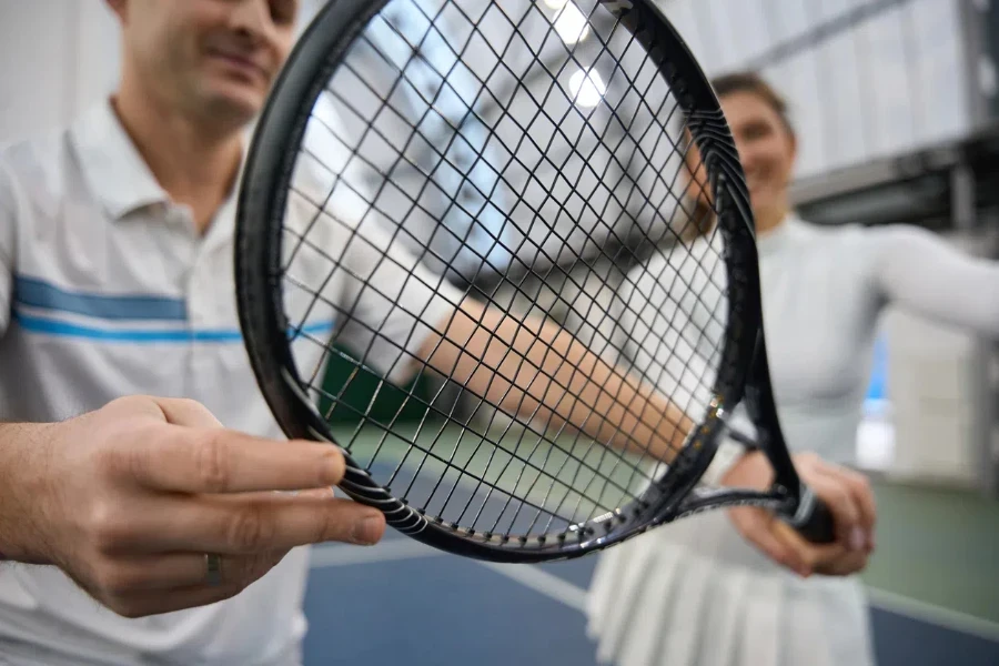 Closeup tangan pemain tenis yang memegang raket tenis bersiap untuk pertandingan di lapangan dalam ruangan