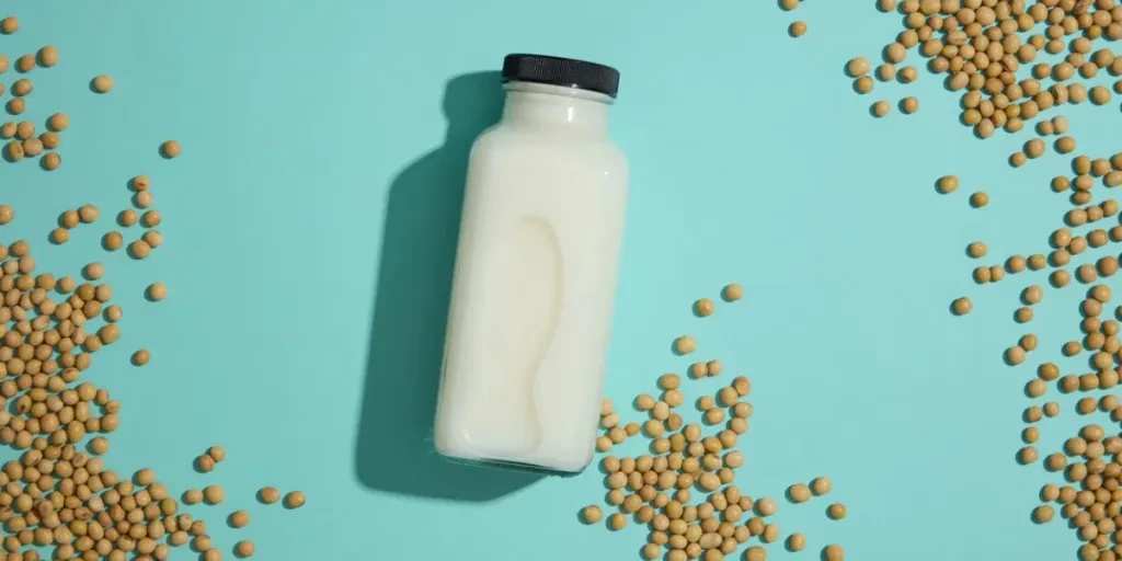 Concept of natural ingredients for branding mockup design with unlabeled milk bottle and soybeans decorated on blue background