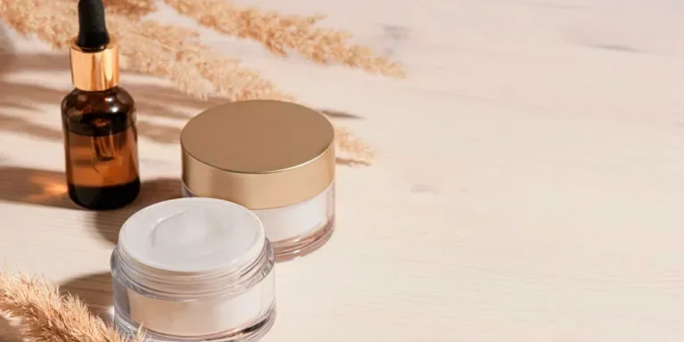 Cosmetic serum and beauty cream products with dry reeds or pampas grass on wooden background