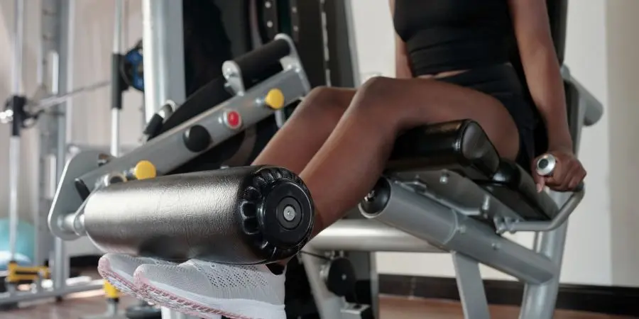 Cropped image of fit young woman doing exercise on leg extension machine