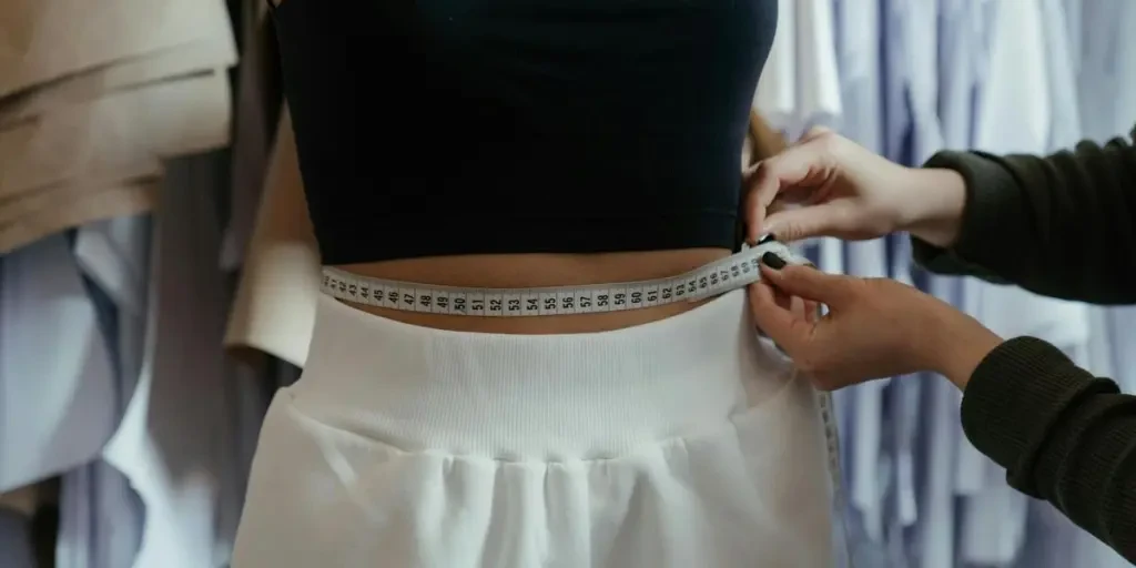 Detailed view of a tailor measuring a clients waist in a clothing workshop, focusing on precision 