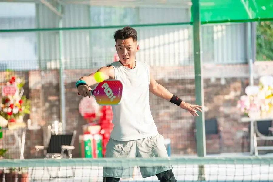 Dynamic shot of a young man playing pickleball indoors in Hanoi, Vietnam