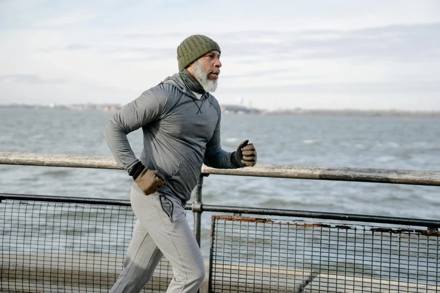 Elderly man jogging on promenade by the sea on a winter morning, showcasing active lifestyle