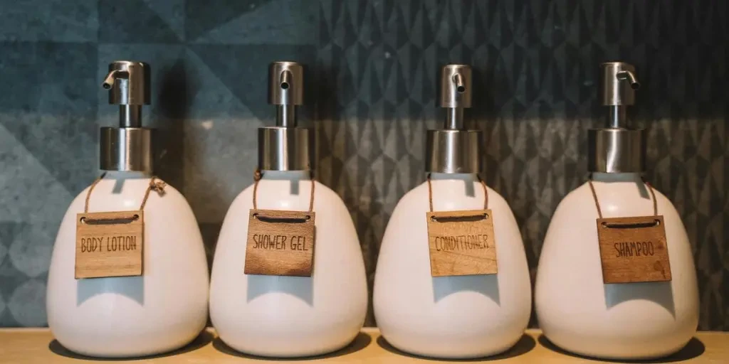 Elegant pump bottles holding bath essentials like lotion, gel, and more on a wooden shelf