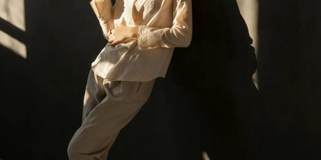 Elegant woman posing stylishly against a wall with dramatic lighting