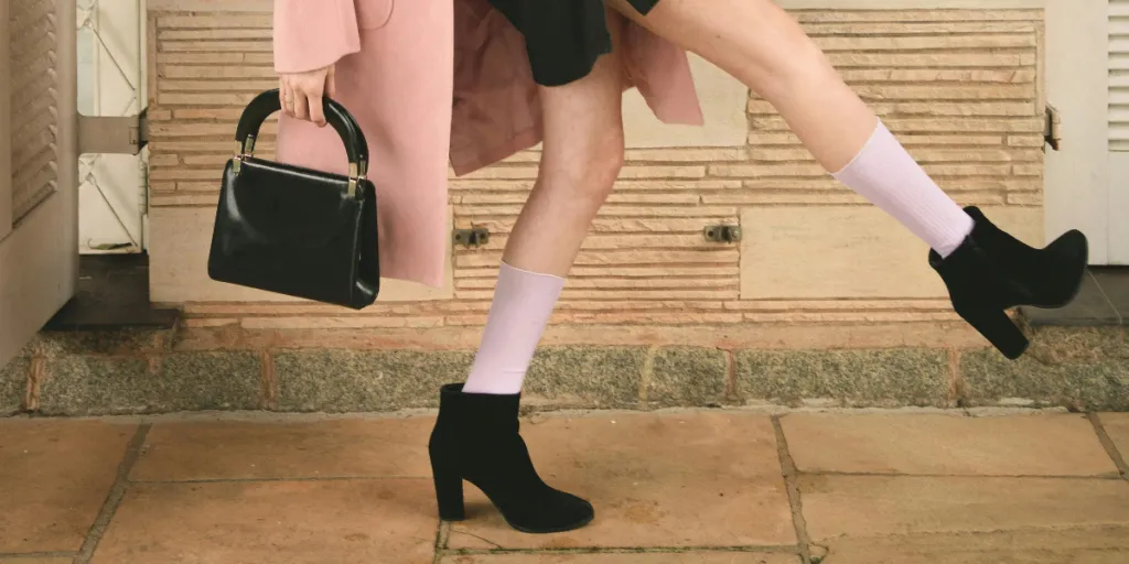 Fashion model in pink coat and black dress striking a dynamic pose indoors with stylish black heels