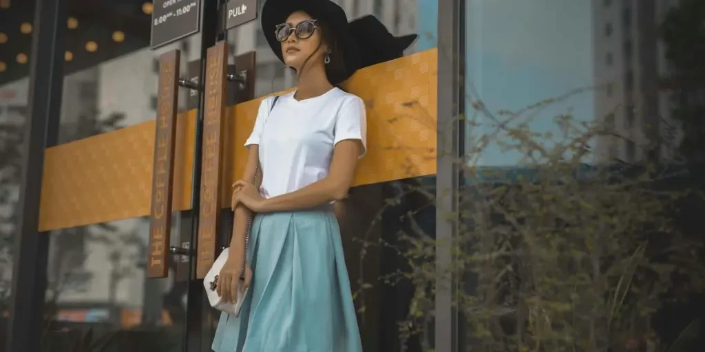 Fashionable woman in hat and sunglasses leans against coffee shop window, embodying urban style