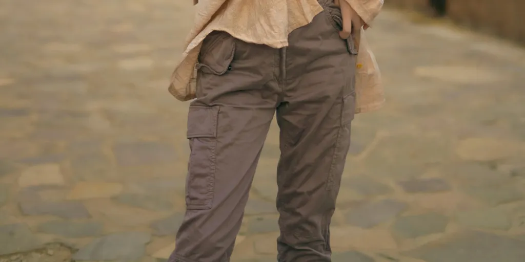 Fashionable woman in tank top and cargo pants posing in a scenic outdoor setting with soft lighting