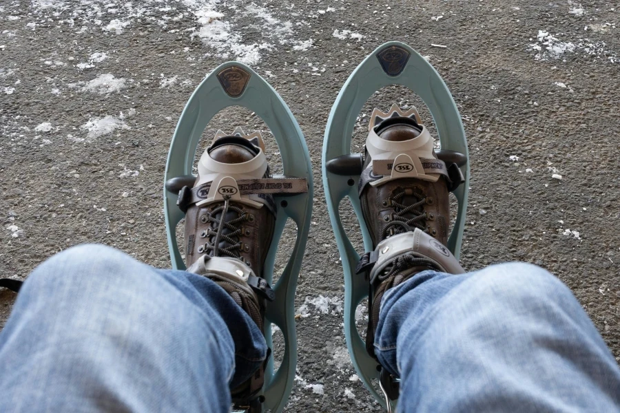 Feet in snowshoes and jeans resting, winter adventure perspective