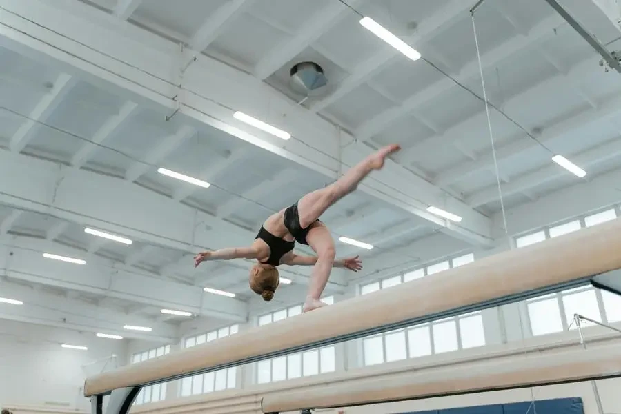 Female gymnast performing an impressive move on the balance beam indoors