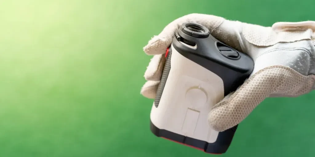 Female hands wearing professional glove with white and black modern optical range finder used for golfing or hunting
