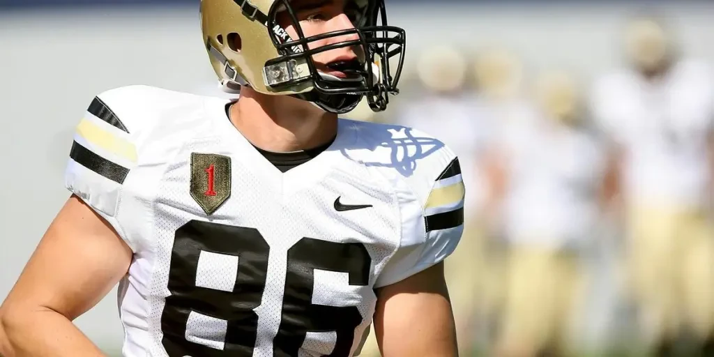 Focused college football player in uniform holding a football during a game