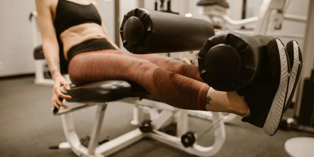 Focused woman exercising on leg curl machine in a fitness gym