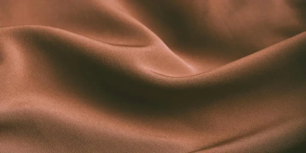 From above of elegant brown draped silk fabric with smooth texture as abstract background