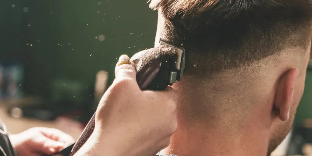 Girl hairdresser makes a haircut to a young guy using