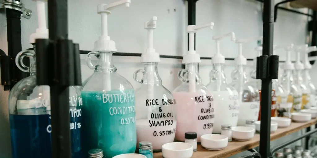 Glass dispensers showcasing a variety of eco-friendly shampoos and conditioners on a wooden shelf