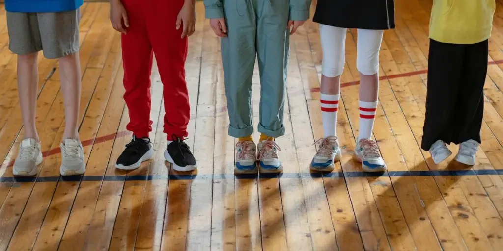 Group of children in colorful sportswear standing on a wooden gym floor indoors