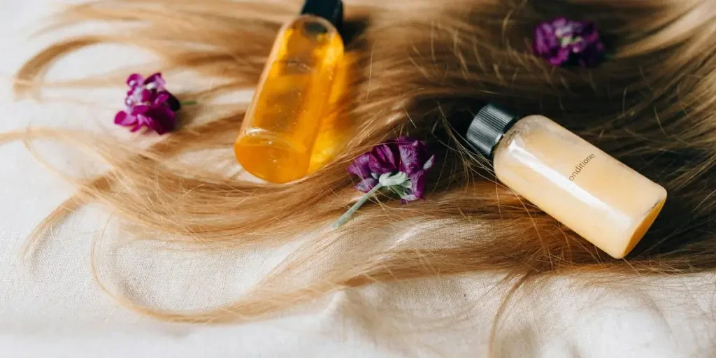 Hair care products on a bed of hair and flowers, symbolizing luxury and beauty