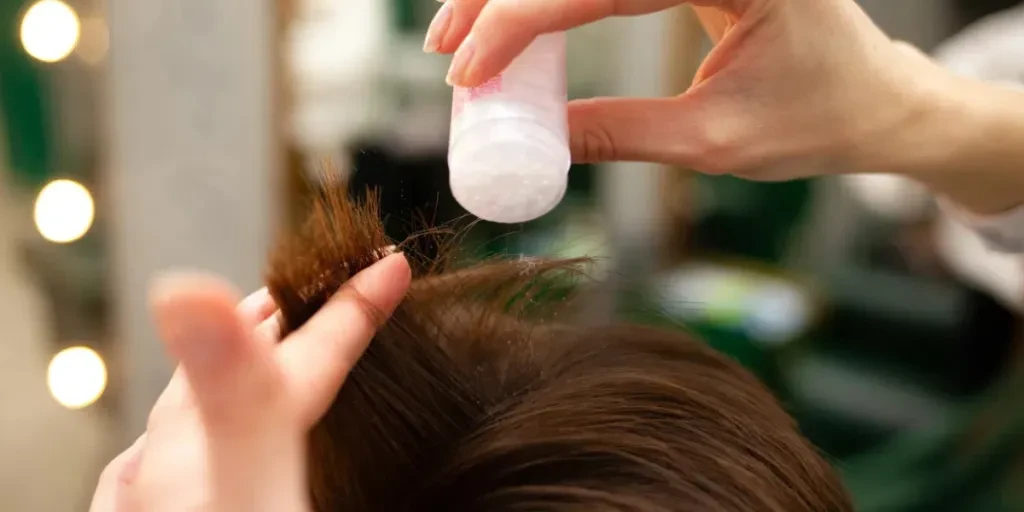 Hairdresser sprinkles the client's head with powdered hair