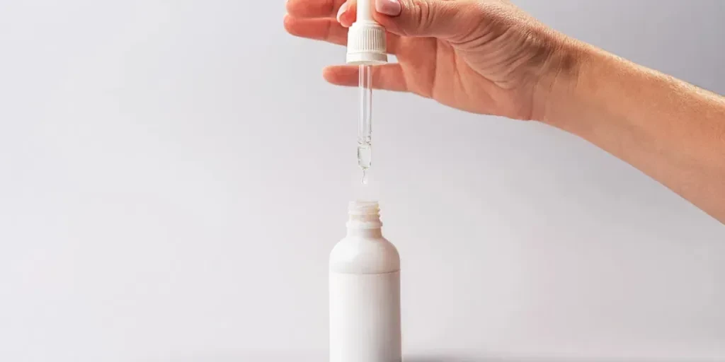 Hand of woman with pipette with drop of serum or hyaluronic