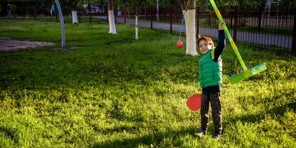 Happy boy is playing tetherball swing ball game in summer camping