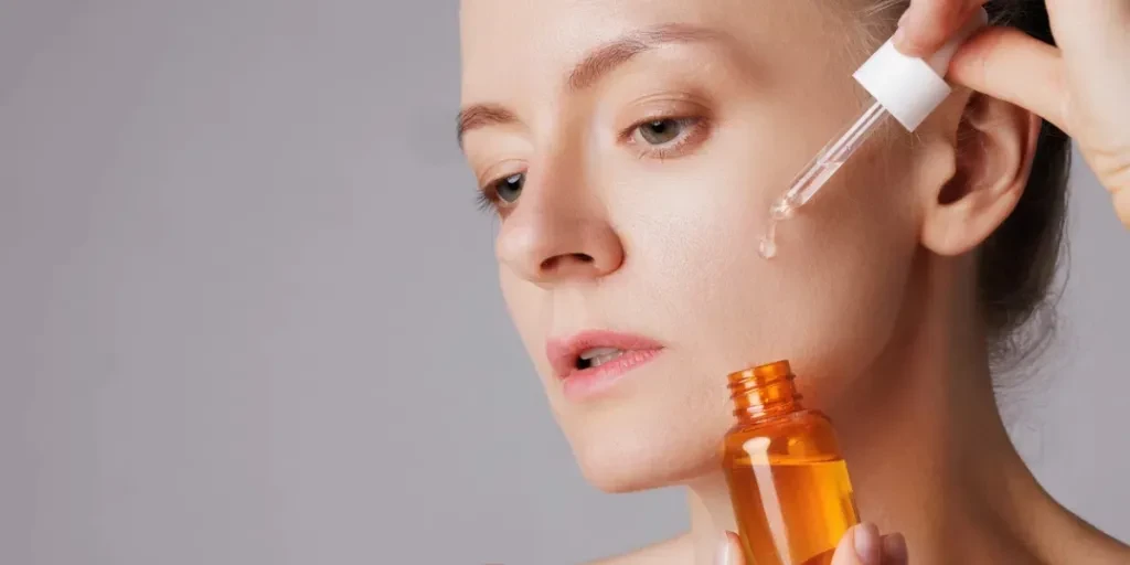 Happy smiling woman applying serum on her face