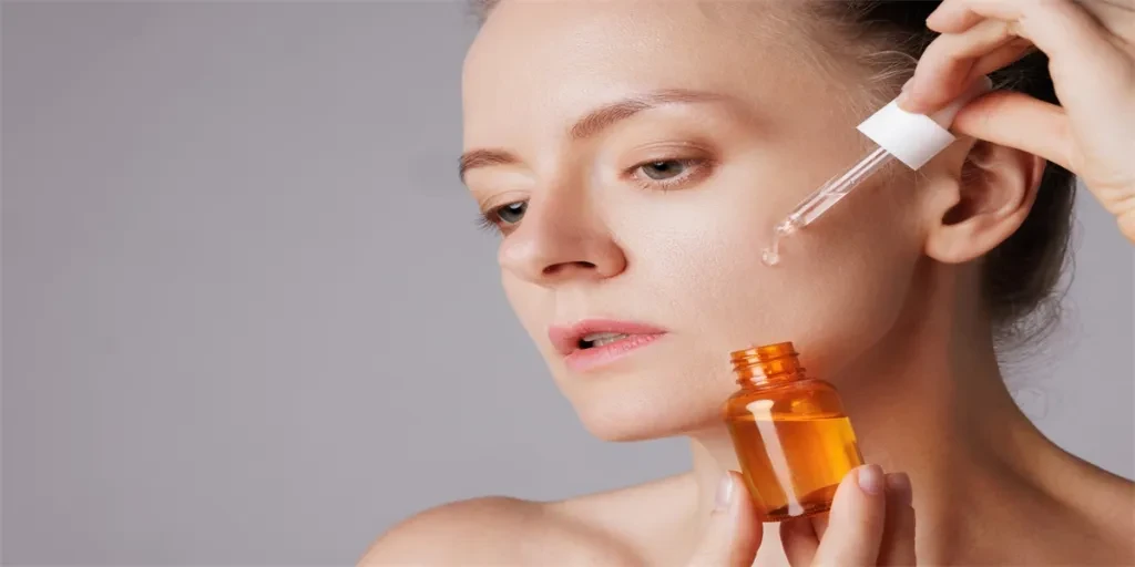 Happy smiling woman applying serum on her face