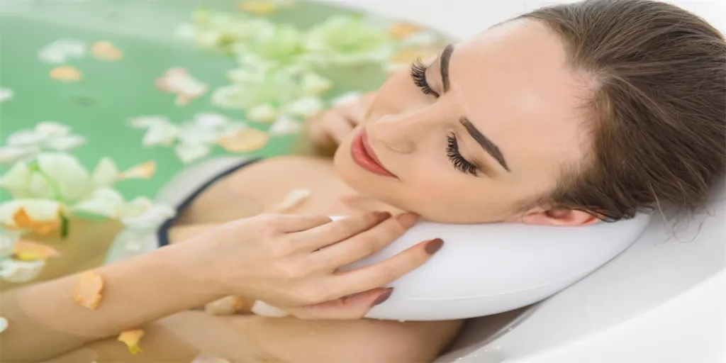 Happy young girl is lying in bath with petals