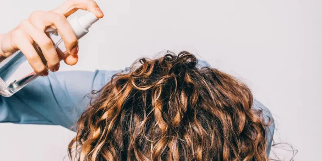 Head of young woman with long curly hair is lowered down to