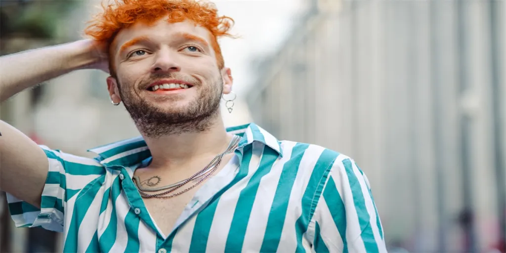 Hipster Gay man in a striped shirt standing on the street and smiling