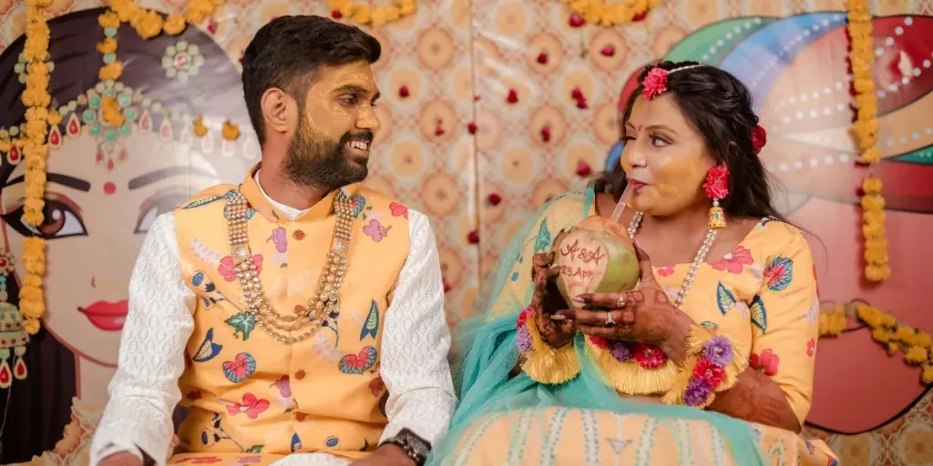 Indian couple in colorful attire celebrating a traditional event in Surat with coconut drink