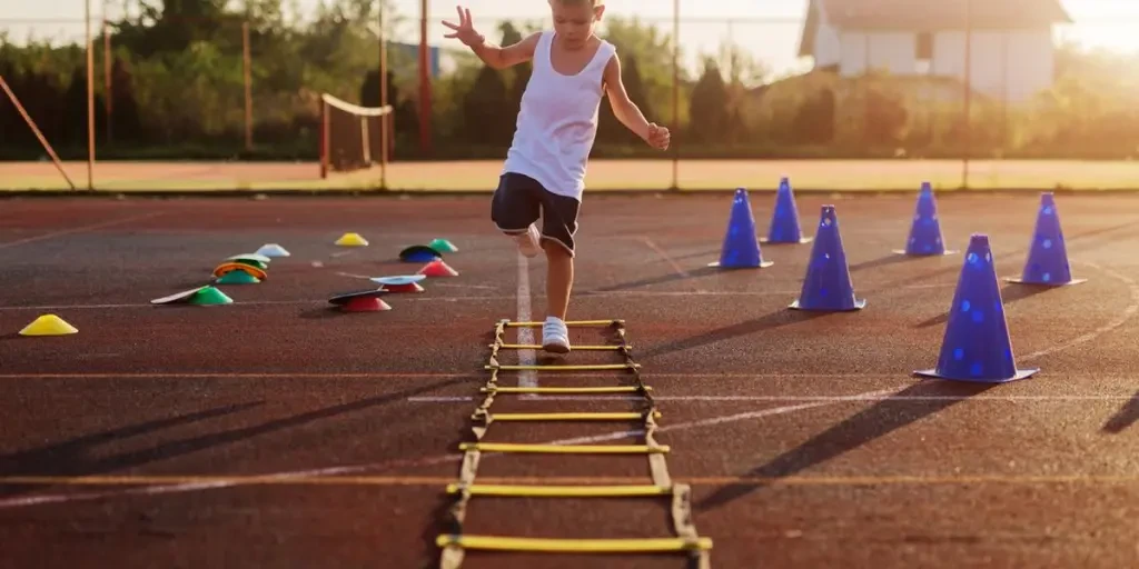 Little boy on early morning summer training jumping over trammels in training field