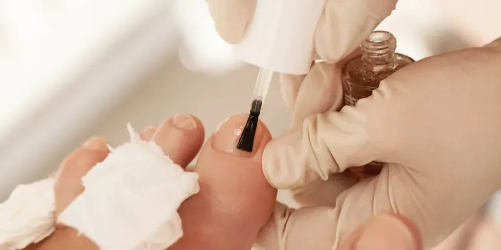 Macro shot of a beauticians hands in gloves applying nail polish to female toenails