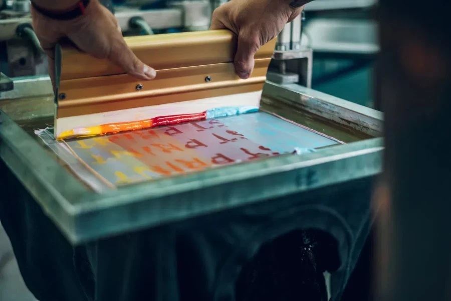 Male worker pressing ink on frame while using the printing machine 