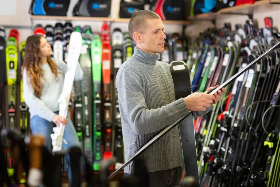 Man choosing new skis in store of sports equipment