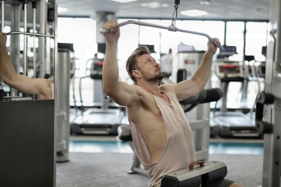 Man exercising on a lat pull-down machine in a modern gym setting