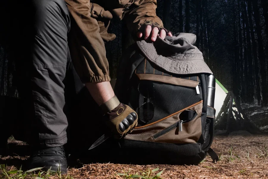 Man in tactical outfit holding a knife and kneeling for backpack