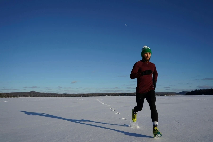 Man running on a snowy field in winter under clear blue skies