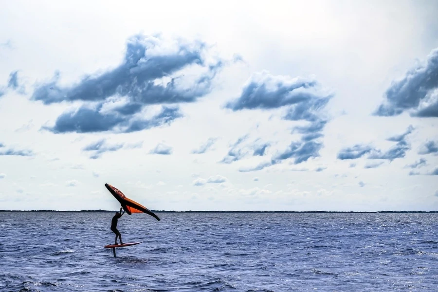 Man waving his wings in calm water and dramatic sky