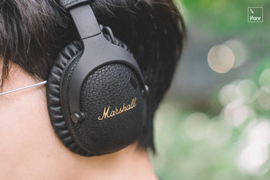 Marshall Monitor III headphones on a wooden table with a plant in the background