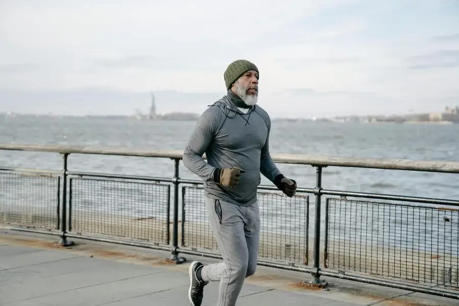 Mature man in activewear jogging by the waterfront, promoting healthy lifestyle and wellness