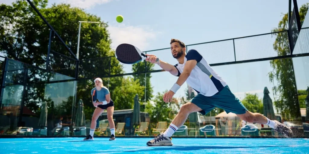 Mixed padel match in a blue grass padel court - Beautiful girl and handsome man playing padel outdoor