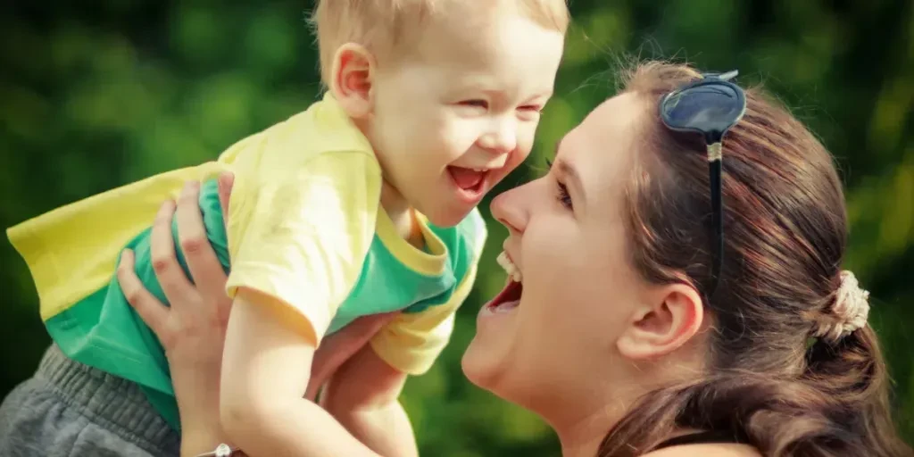 Mom rise up her son on her hands and happily plays with him