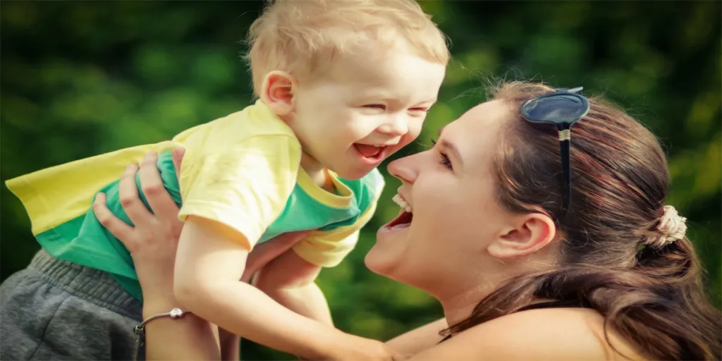 Mom rise up her son on her hands and happily plays with him