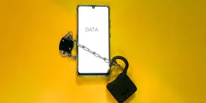 Phone security concept. Smartphone locked with chain and padlock on yellow background. Mobile security and data privacy