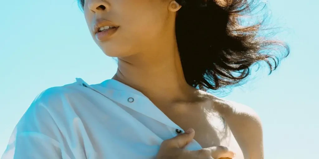 Portrait of a woman with long hair in a white shirt, outdoors, wind blowing