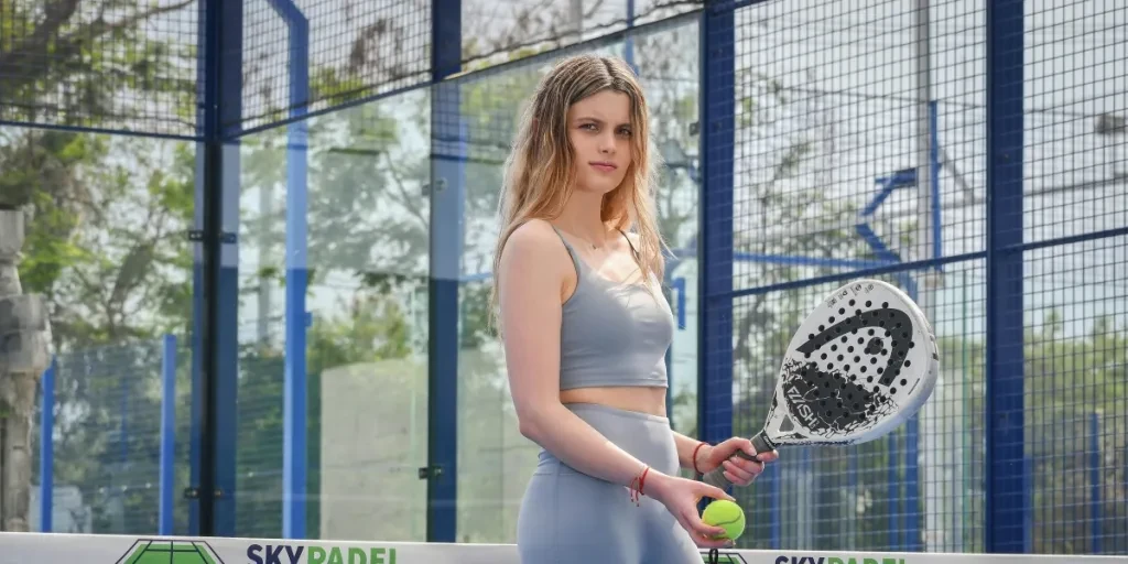 Portrait of a young woman holding a padel racket outdoors on a sunny day